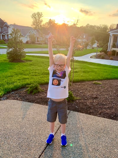 its-a-decade-of-declan-2-boy-with-hands-raised-in-sunshine