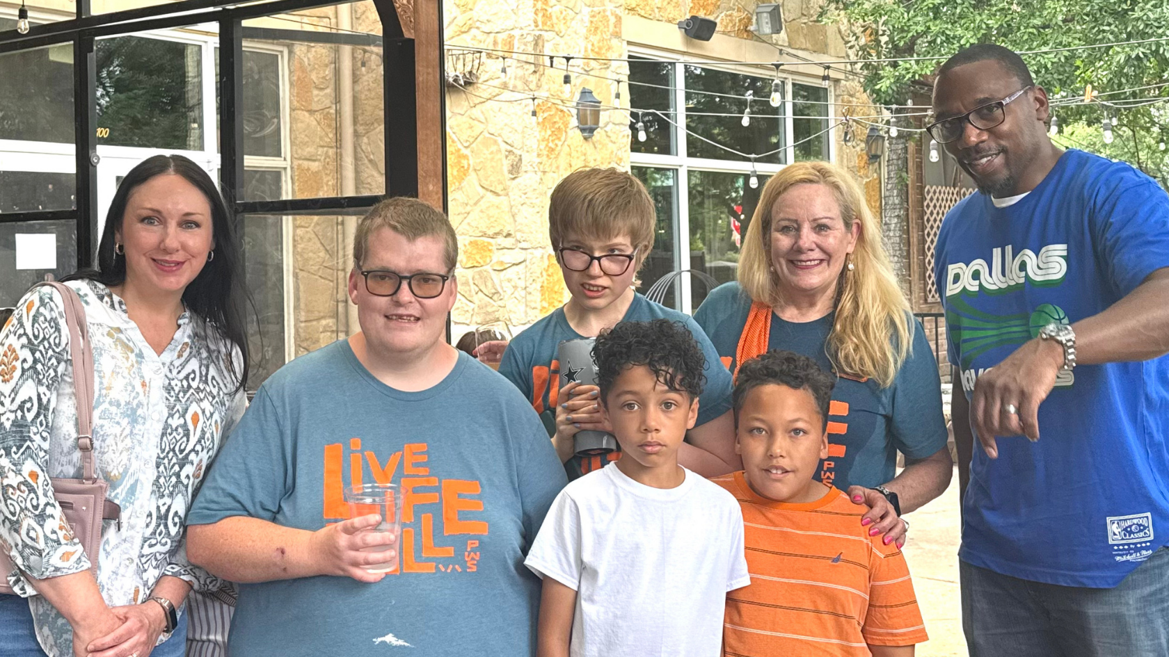 Adults and children pose together at HopeFULL Dallas, with several wearing “Live Life Full” PWS shirts.