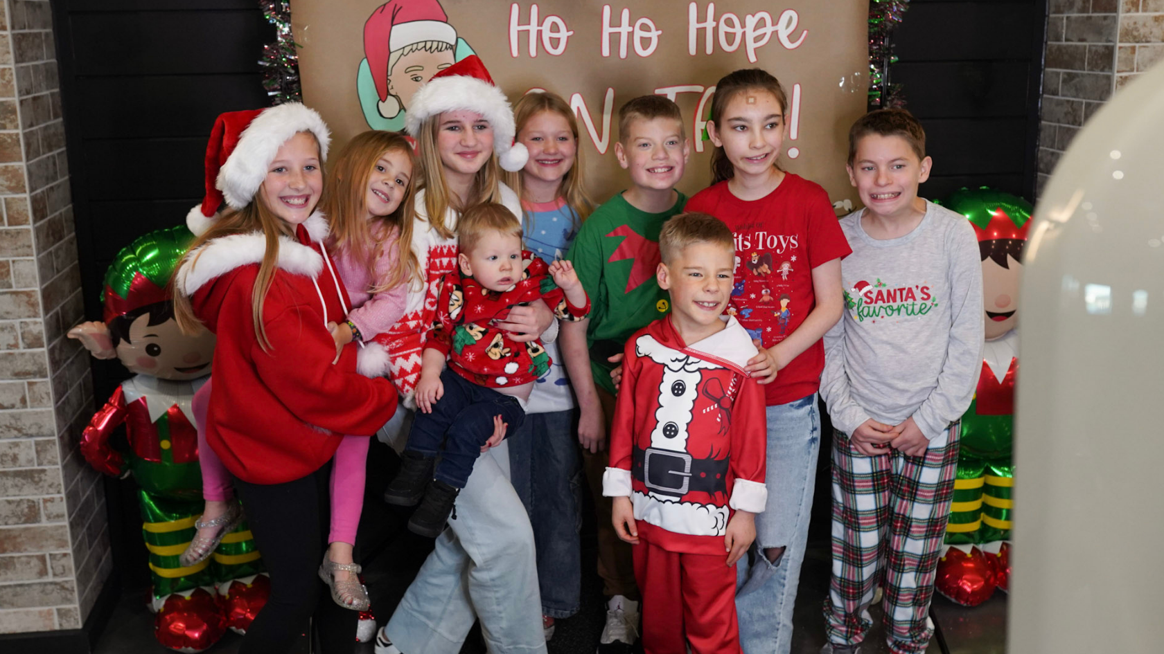 Group of children smile together in festive clothing at a holiday Bingo event.