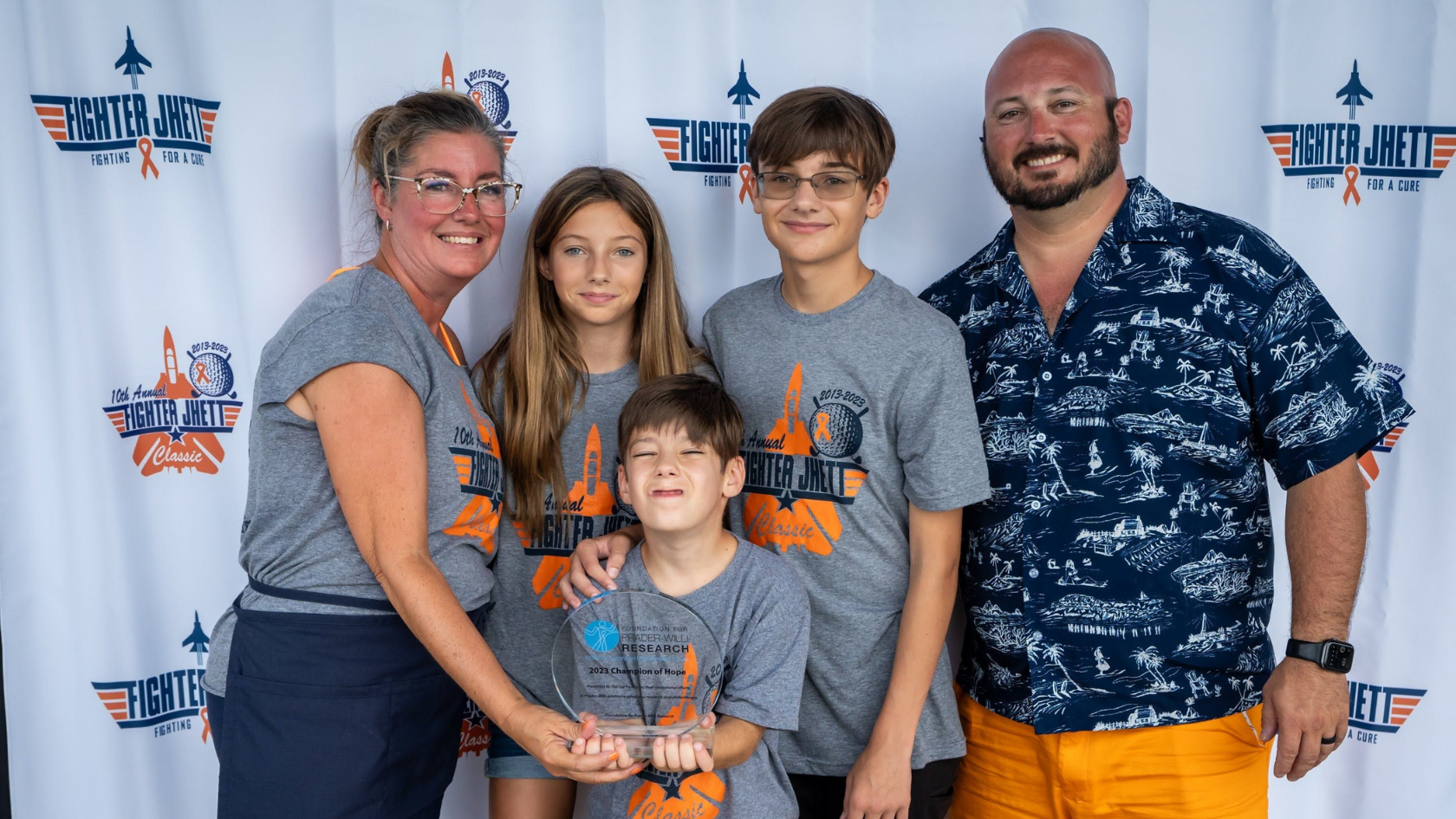 Family poses at the Fighter Jhett Classic while holding an FPWR Champion of Hope award.