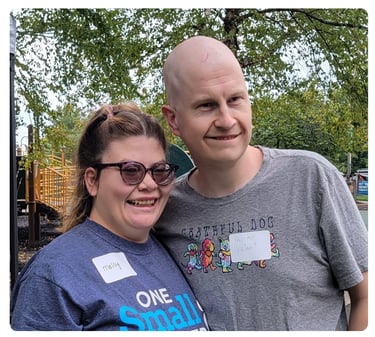 Young woman wearing glasses smiling with a man outdoors at an FPWR event.