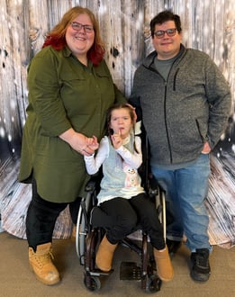 The Gault family smiling in front of a glittery background.