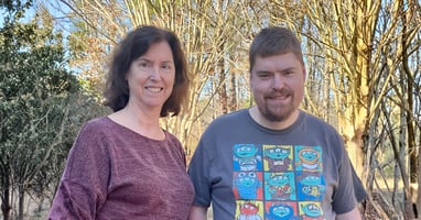 Dr. Theresa Strong and her son Daniel smiling together outdoors in front of trees.