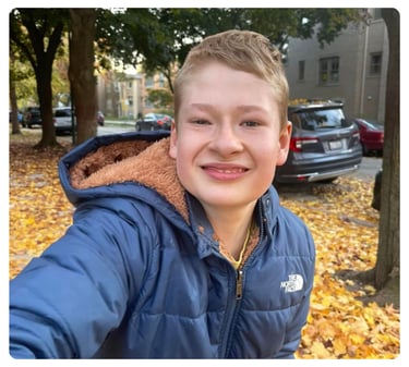 Young man smiling outdoors while wearing a blue jacket.
