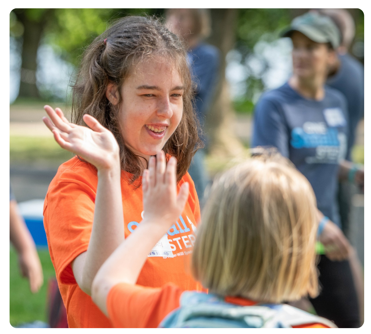 Young woman smiling and raising her hands while interacting with another person at an outdoor FPWR event.