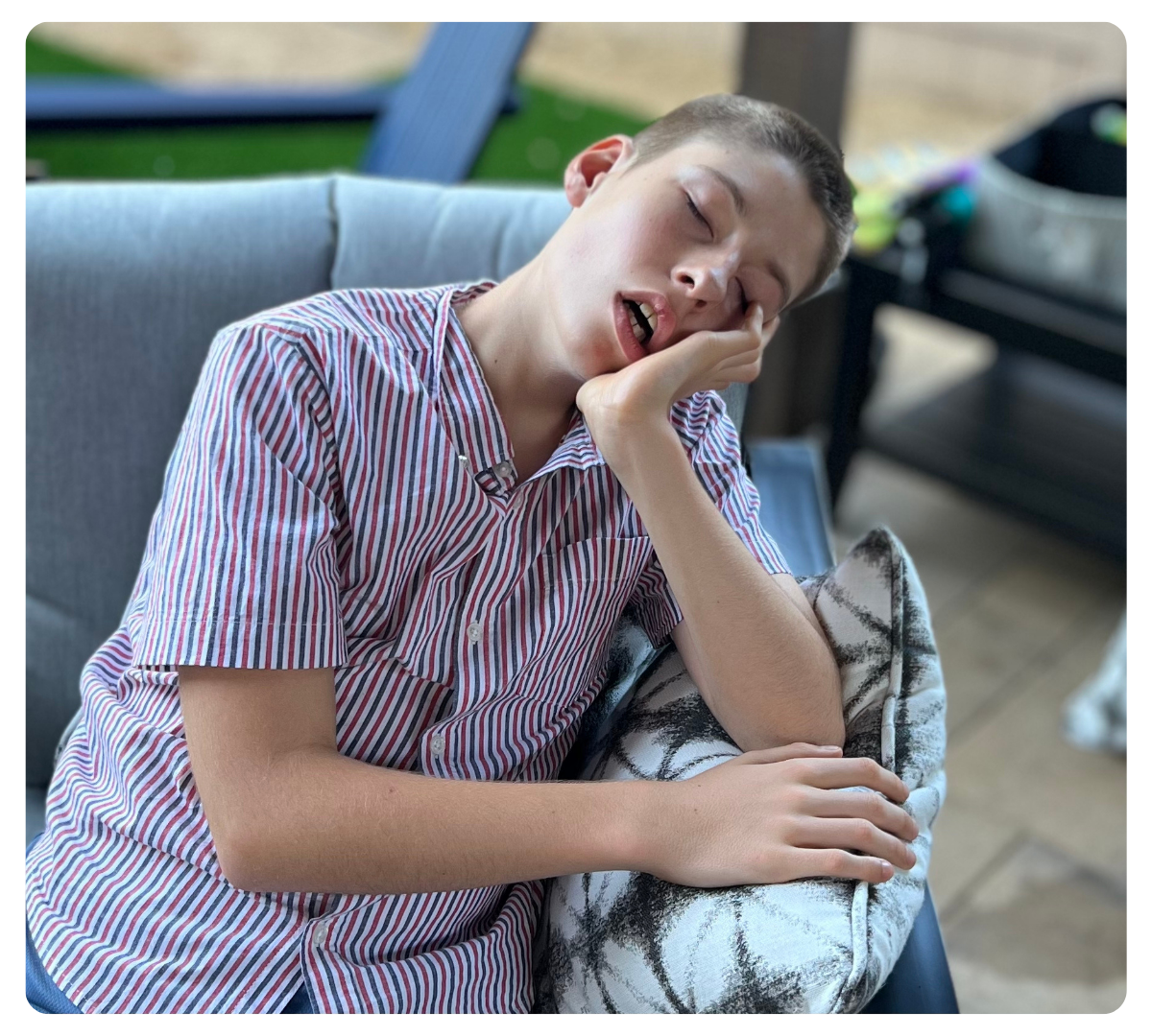 Young man resting his head on his hand while seated on a couch.