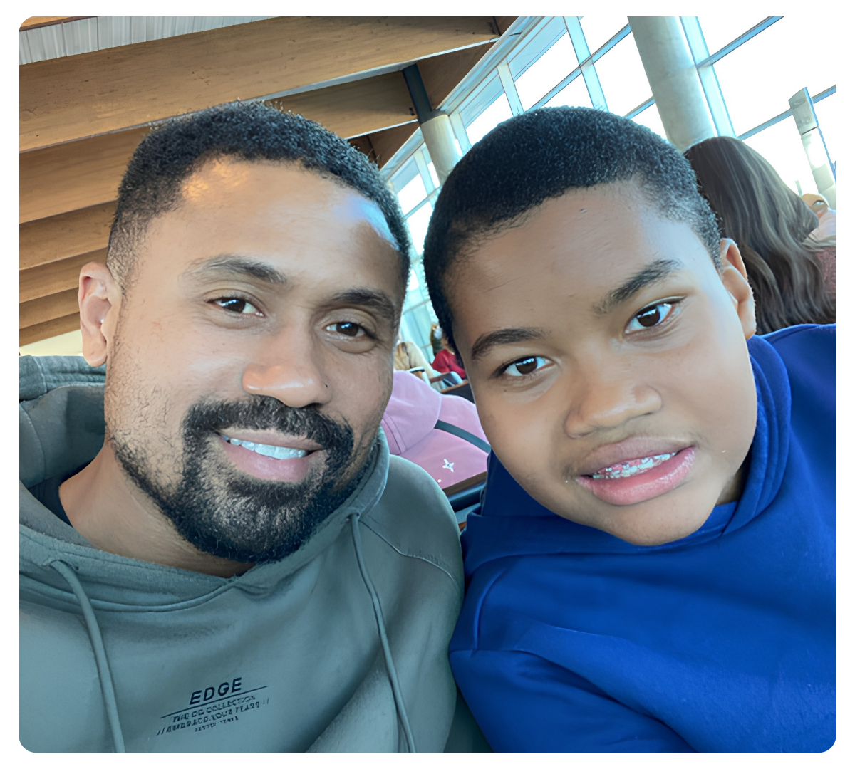 Man and young man smiling together for a selfie indoors.